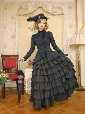 Full front view of Victorian Gothic Lolita tailed hem blouse and multi-layer skirt set in all-black, worn by model in vintage retro room with feather-decorated top hat