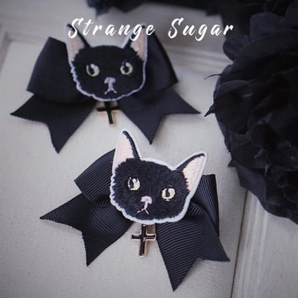 Black cat embroidered bow lolita hair clips pair with cross pendant displayed on light beige background with dark flowers