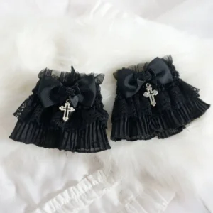 Gothic Lolita black lace wrist cuffs pair with layered ruffles, black satin bow, fabric rose and silver cross pendant in flat lay view