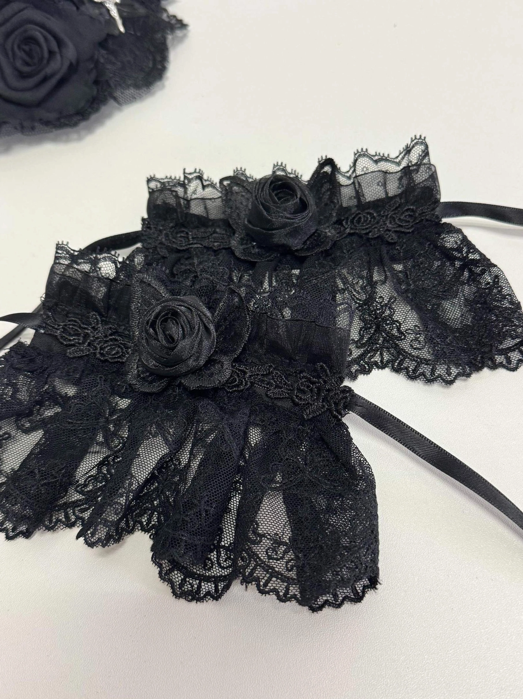Gothic lolita black lace neck corset accessory with 3d fabric rose decorations scalloped ruffled hem adjustable fastening strap close-up flat lay