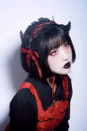 Gothic lolita headband back tilted side view displaying wing ornament and red ribbon tie at nape model in red-black gothic maid outfit