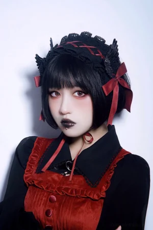 Gothic lolita black red handmade hairband front three-quarter view showing black lace base with crossover red ribbons red side bows and black wing ornaments on model wearing gothic lolita dress