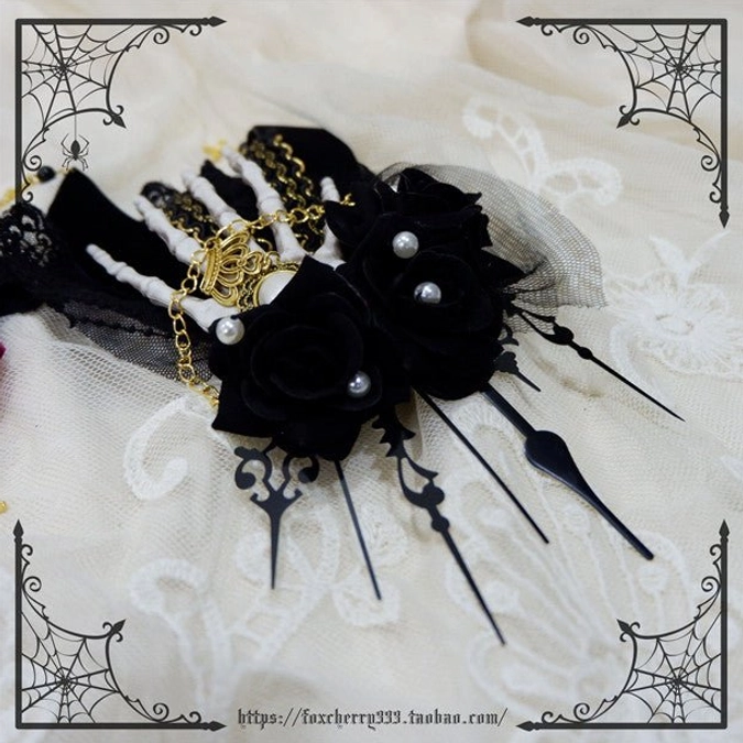 Black rose skeleton hand hair clip flat lay lace fabric multiple black roses pearl details gold chains spike accents