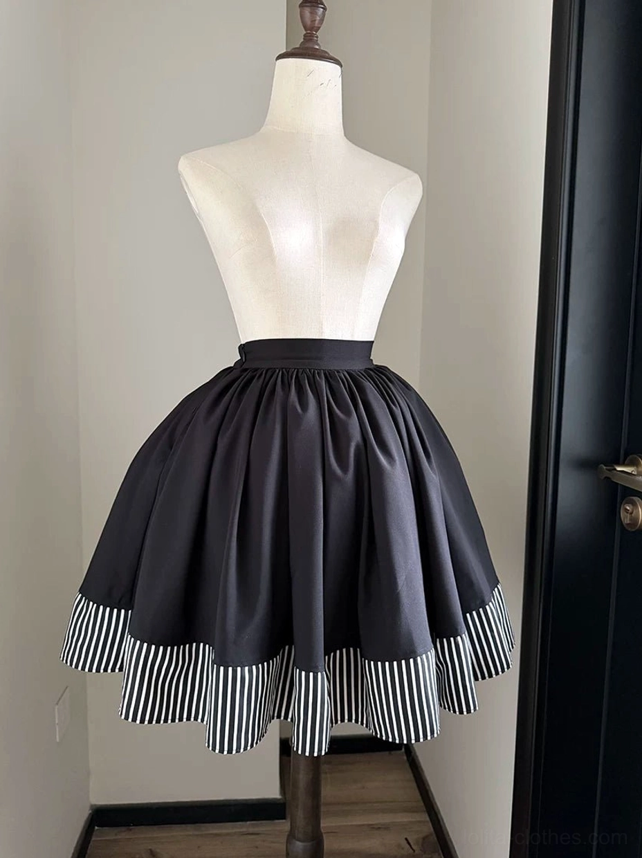 Gothic lolita black skirt with black and white striped hem three-quarter front view on dress form showing full pleated silhouette and striped ruffled trim