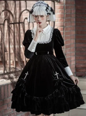 Black velvet Gothic Lolita OP dress front view with white lace collar, pearl cross embroidery, tiered poufed skirt, and contrast white cuffs on model with gothic hairstyle