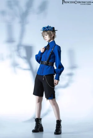 Three-quarter side full-body view of Gothic Lolita formal outfit with royal blue tailored blouse, black shorts, blue floral hat, leather waist belt, androgynous male model in theatrical studio setting