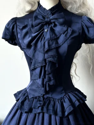 Navy blue Gothic Lolita fitted blouse close-up front view dress form stand collar ruffled bow detail puff sleeves layered flounce hem