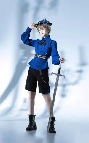 Full-body front view of Gothic Lolita prince-style outfit featuring royal blue blouse with pleated front, black tailored shorts, blue floral top hat, waist belt with decorative chain, photographed against dramatic candelabra shadow background