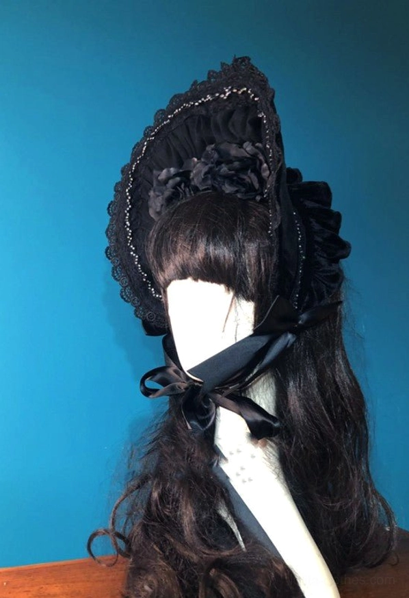 Black gothic lolita velvet half bonnet right side view featuring rear ruffled velvet panel, satin chin tie bow and decorative fabric flower accent