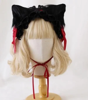 Gothic Lolita cat ear headband with detachable black faux fur ears and black lace ruffled trim on mannequin with blonde wig, frontal view displaying red satin bows