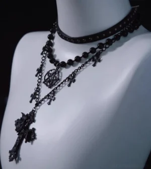 Three-quarter side view of triple-layer Gothic Lolita necklace showing asymmetrical long hanging cross pendant and layered gothic chain set with matching decorative charms on white display mannequin