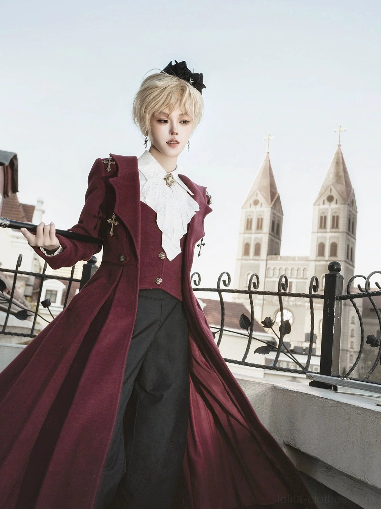 Close-up front three-quarter view gothic ouji lolita winter coat detailed neck ruffled cravat cross brooch structured coat shoulders wooden walking cane vintage aesthetic
