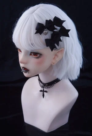 Gothic Lolita black bow hair clips with cross pendant displayed on BJD doll wearing dark makeup left three-quarter view
