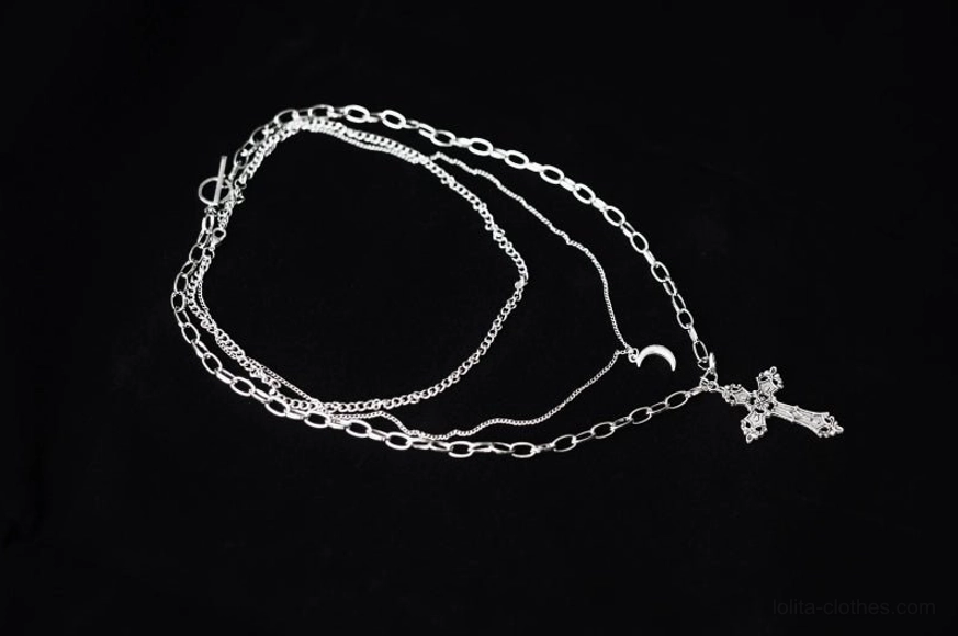 fully spread out gothic lolita necklace components on black background showing complete triple-layer chain configuration with silver-toned metal finish, carved cross pendant, crescent moon charm and mixed chain link styles