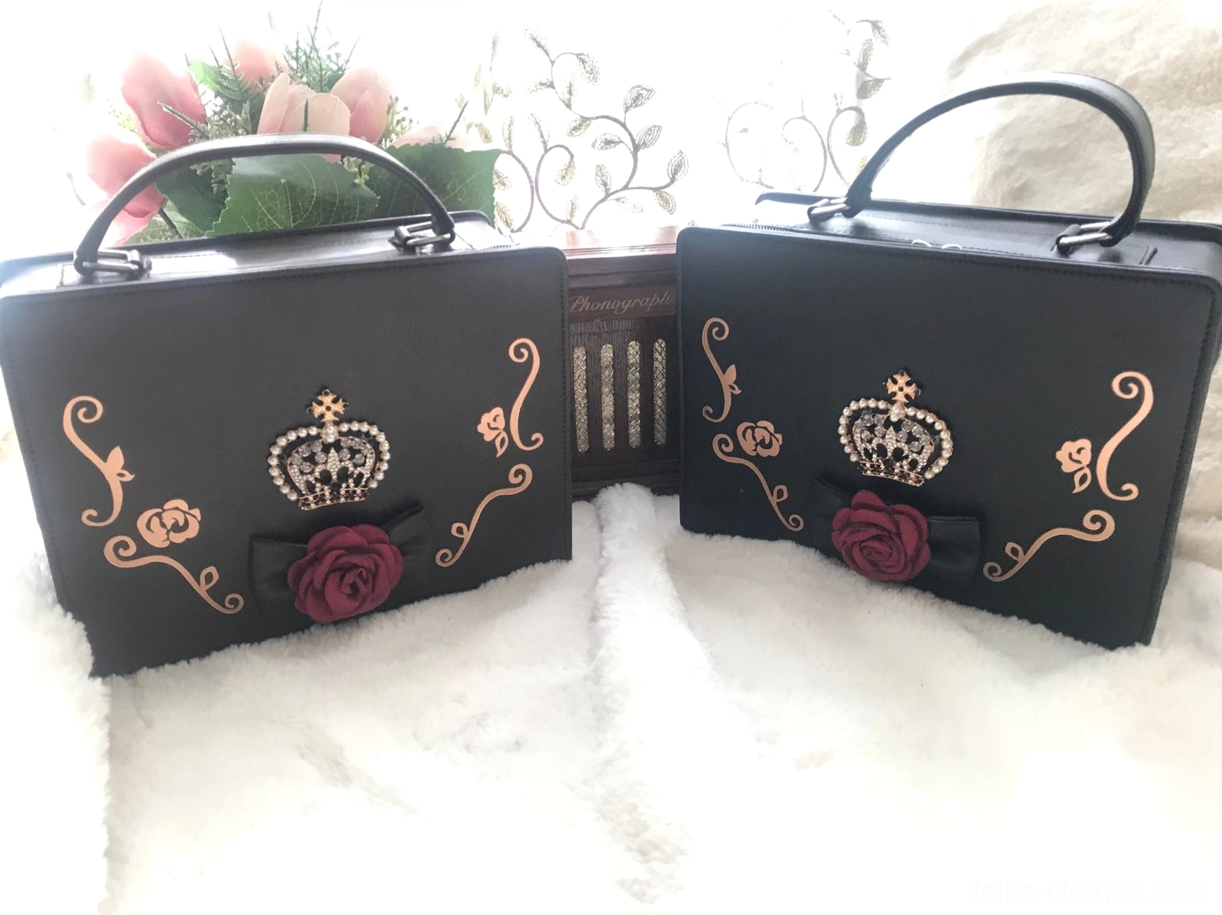matching pair of black and dark brown gothic lolita crown handbags flat lay high angle view white fuzzy background jeweled crown red rose black bow golden scroll motifs
