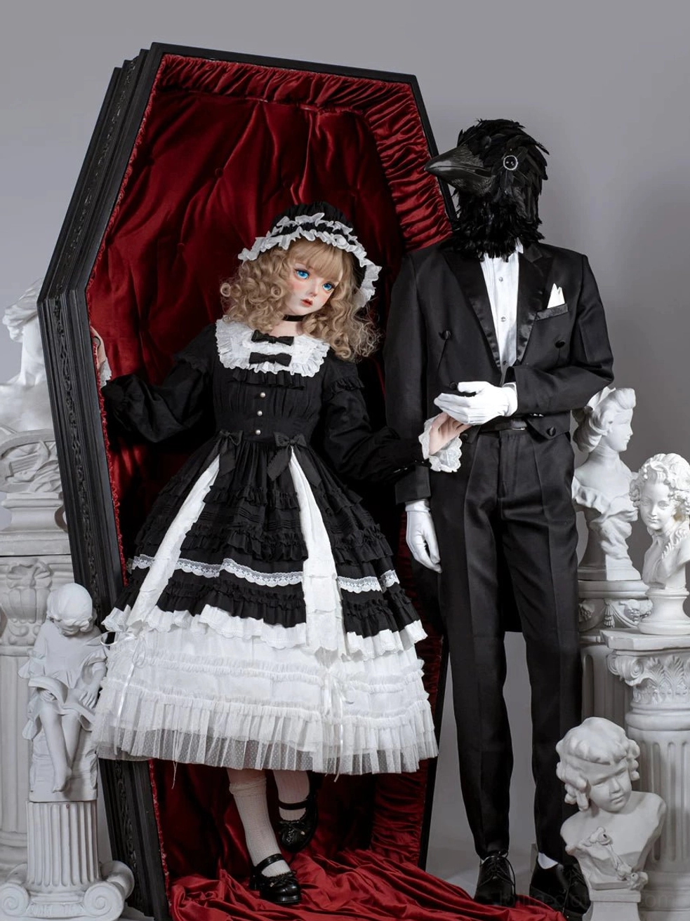 Gothic lolita one-piece dress with black and white color block, frilled collar, tiered ruffled skirt, and matching hair headdress on mannequin vintage display