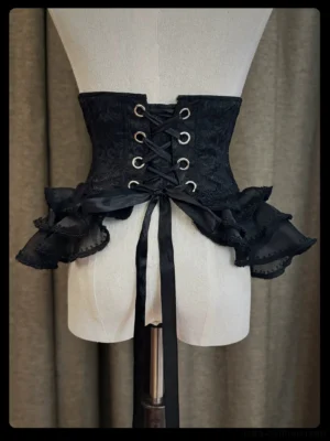 Gothic lolita black corset waist cincher back view displaying lace-up closure with metal eyelets and long drawstring ties layered ruffled tulle side flounces