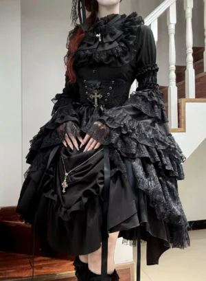 Black Gothic Lolita four-piece set worn by red-haired model on indoor staircase, featuring stand-collar blouse with ruffled lace, layered trumpet sleeves, dramatic poufed-hem skirt, six-bone cincher waist overlay with metal cross pendant and dangling chain, black gloves and boots