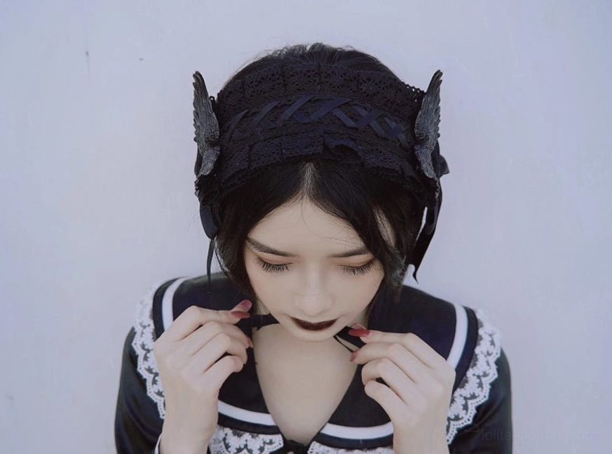 Front close-up portrait model wearing sailor lolita dress with black lace headband side wing and bow decorations studio grey background