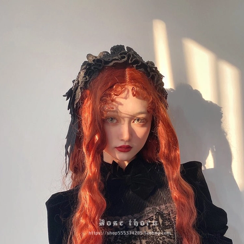 Black lace gothic lolita headband close-up frontal shot featuring wing-shaped embroidered pendant and ruffled lace border, all-black color scheme