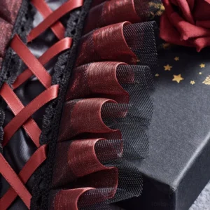 Close-up detail view of Gothic Lolita hair accessory showing cross-laced wine red satin ribbons, ruffled mesh frills and layered black tulle fabric construction