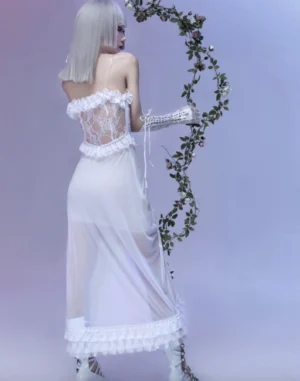 Back view of white gothic lolita jumper skirt showing sheer mesh lace back cutout detail, floor-length ruffled asymmetrical hem, waist lace-up details, and matching lace gloves