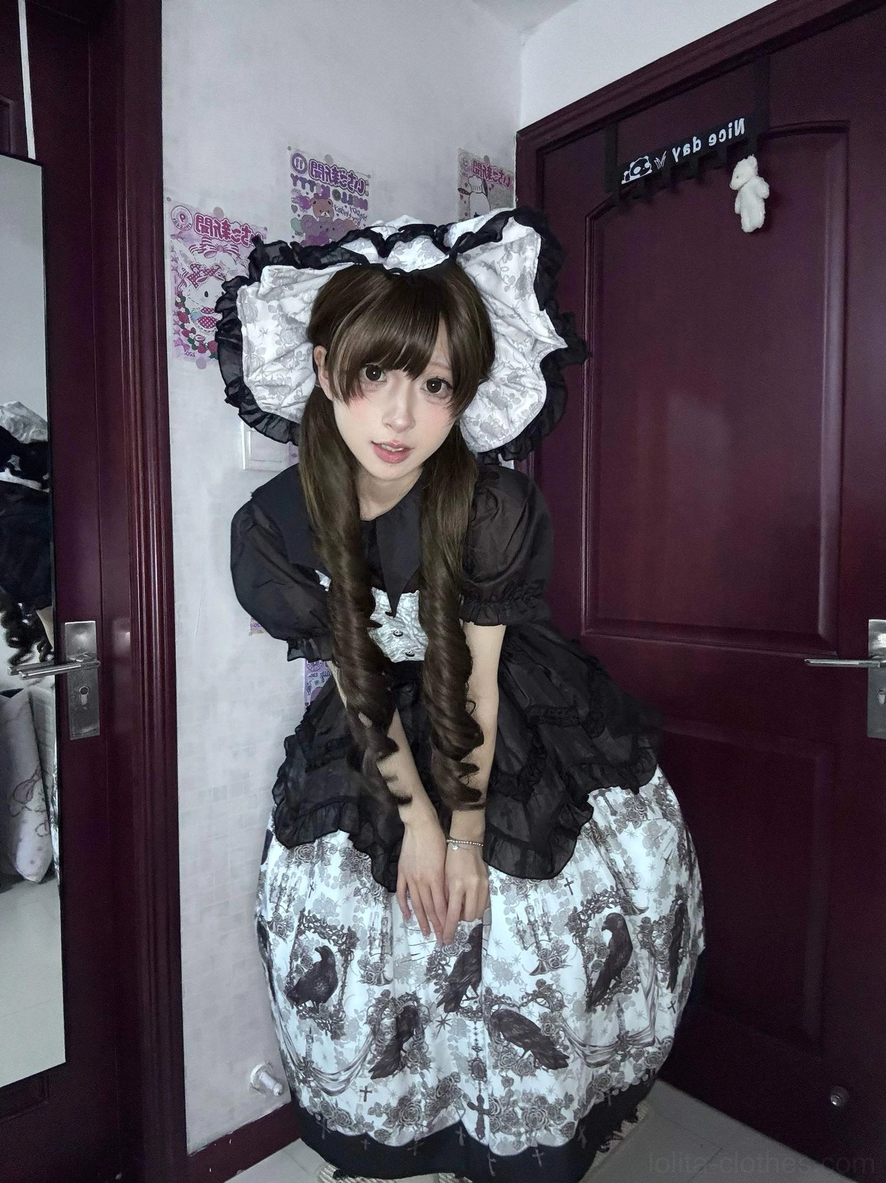 Gothic lolita model squatting wearing crow print JSK dress with detachable waist tie black ruffled blouse and matching headbow coordinate