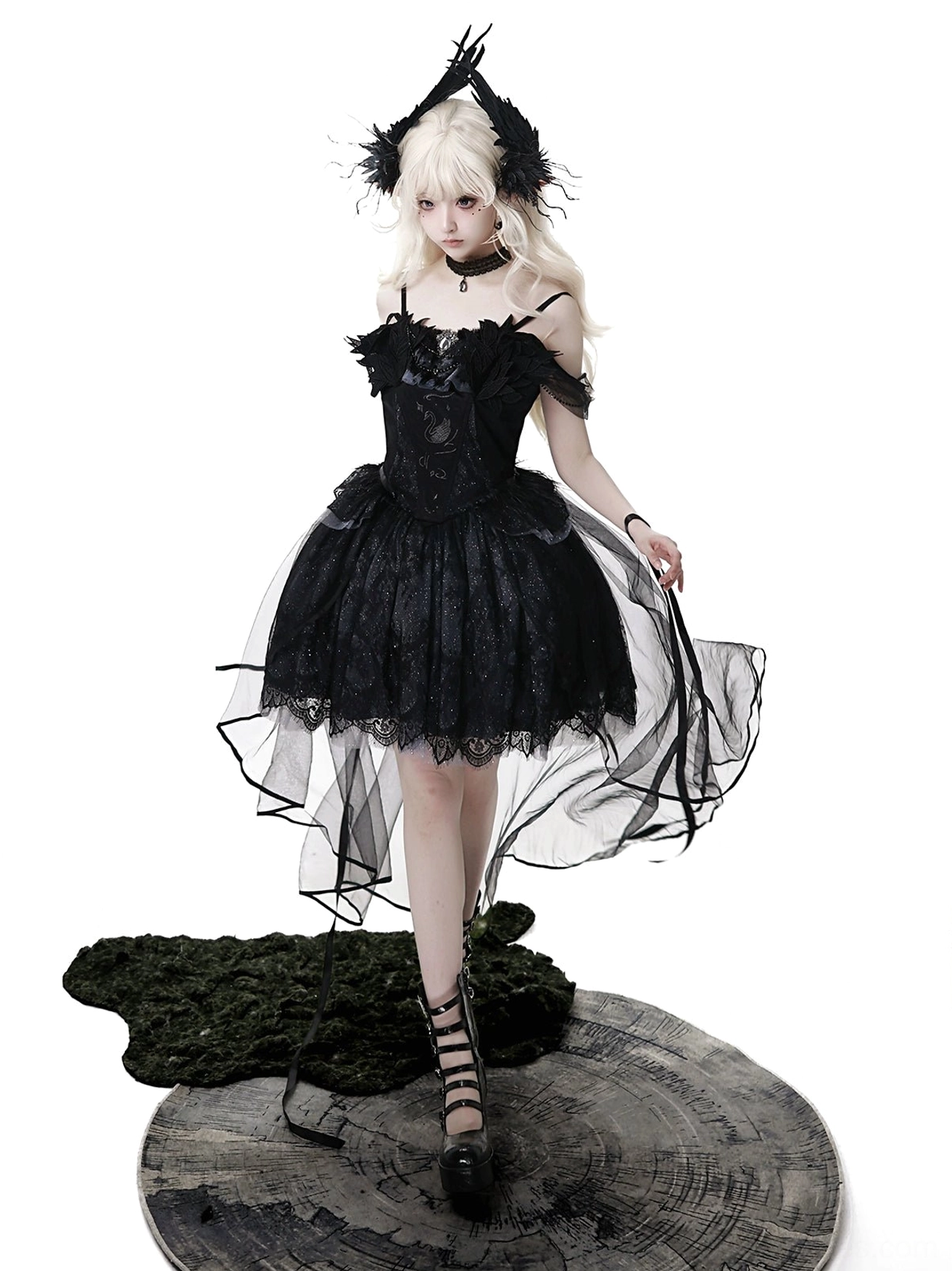 Black gothic lolita JSK dress front-side angle on blonde model wearing feather gothic headpiece, ruffled off-shoulder lace bodice with short inner skirt and sheer trailing tulle panels