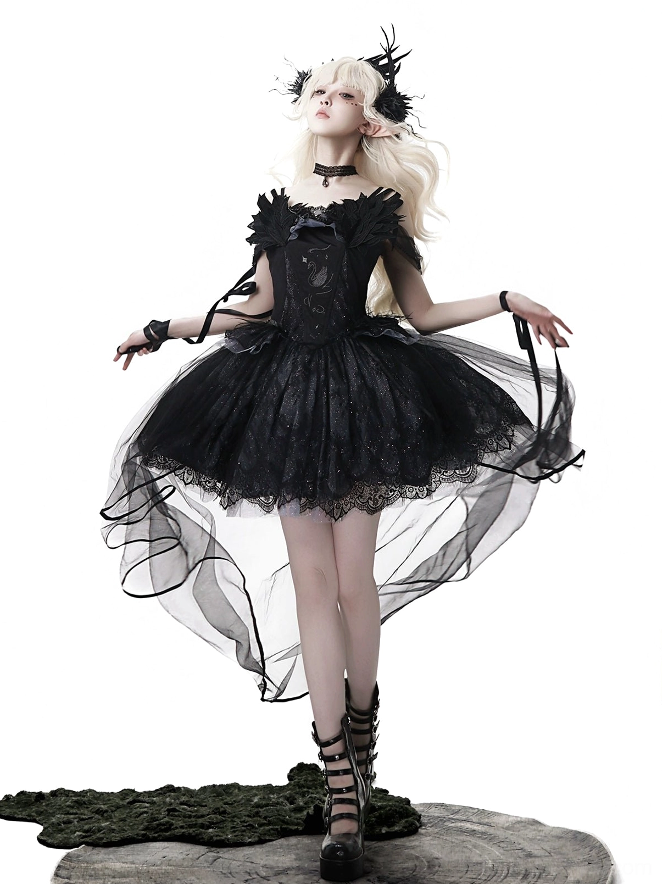 Black gothic lolita jumper skirt with swan embroidery worn by blonde model on mossy base, featuring off-shoulder lace bodice and high-low tulle train skirt