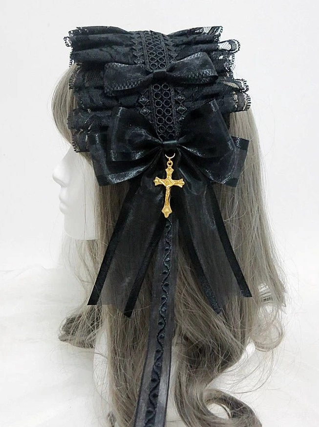 Gothic lolita KC hairband with gold cross pendant worn on mannequin, rear three-quarter view showing layered black lace, large satin bow, flowing ribbon tails, and ornate cross charm detail