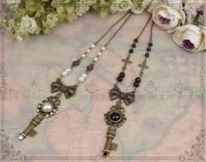 Close-up overhead view of gothic lolita key pendant necklaces showing antique bronze bowknot hardware white pearl and black gem inlaid key charms with mixed pearl bead chains