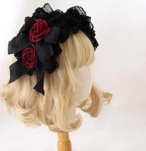 Gothic Lolita black ruffled lace KC headband with two burgundy fabric roses and black bows, worn on blonde curly wig mannequin head, left three-quarter view showcasing layered lace design and rose embellishments