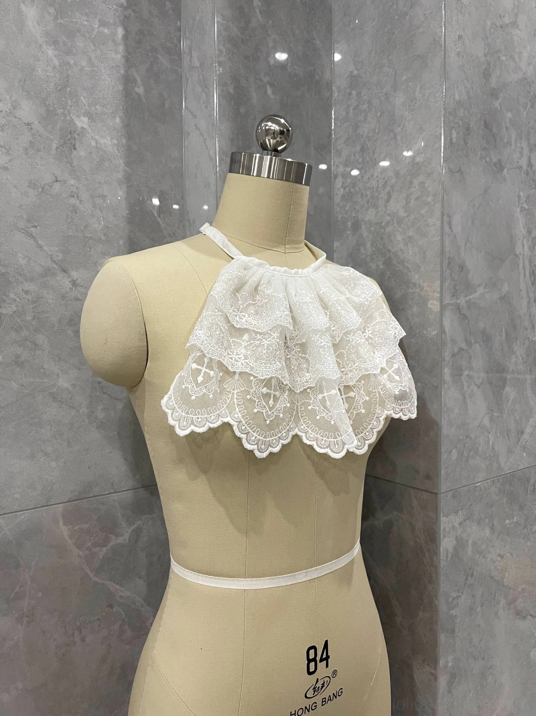 Three-quarter view of white Gothic Lolita lace neck bib with layered ruffles and adjustable halter strap