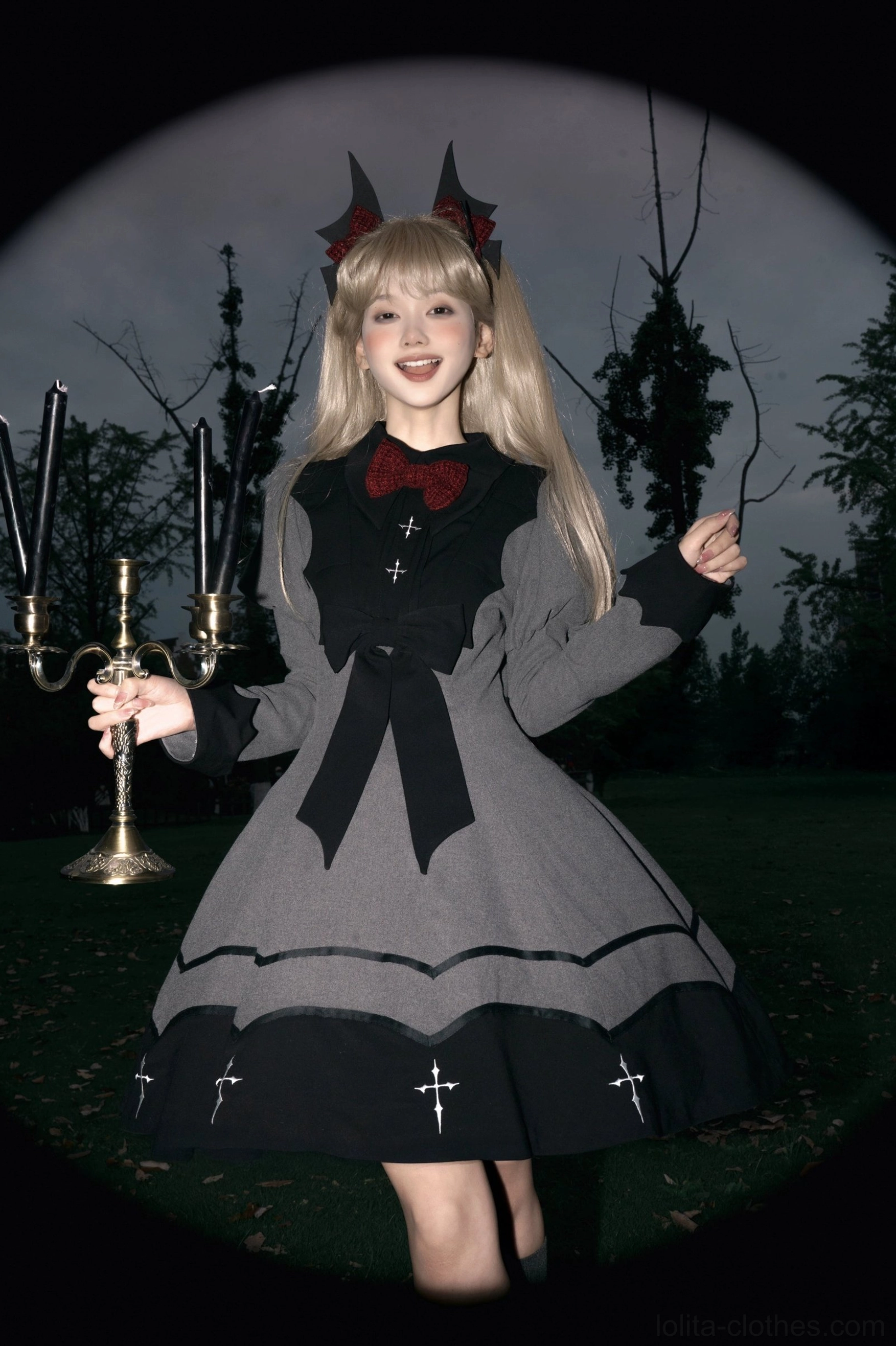 Vampire princess bat-inspired Halloween gothic lolita OP dress front view with red bow and cross embroidery on model wearing devil horns
