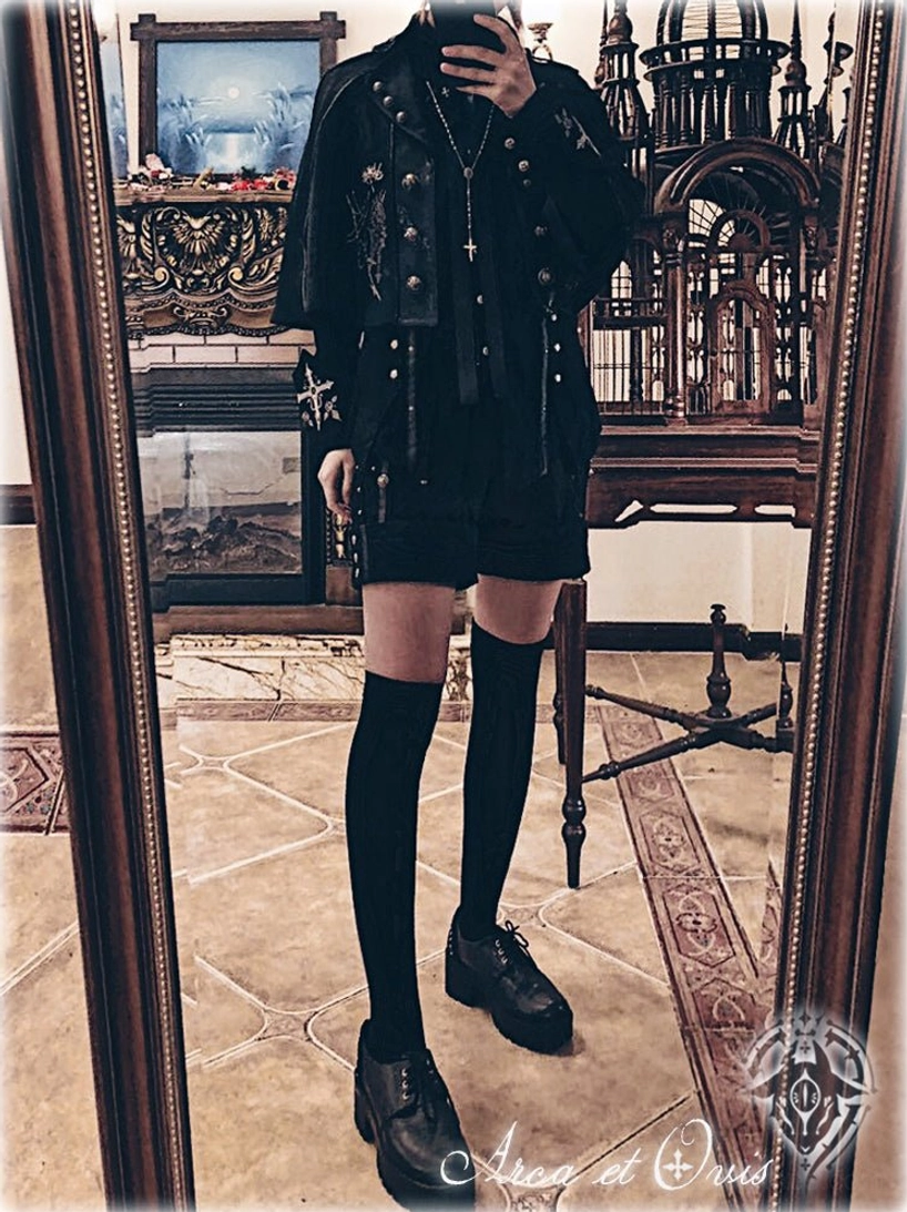 Full-body side view Gothic Ouji Lolita coordinate in vintage gothic indoor setting with cross pendant necklace, layered black outfit, matching silver embroidery on cape and coat details