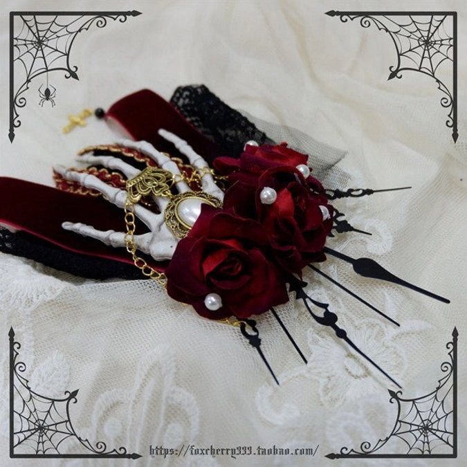 Gothic skeleton hand hair clip red roses flat lay lace fabric background pearls gold chains black spike decorations