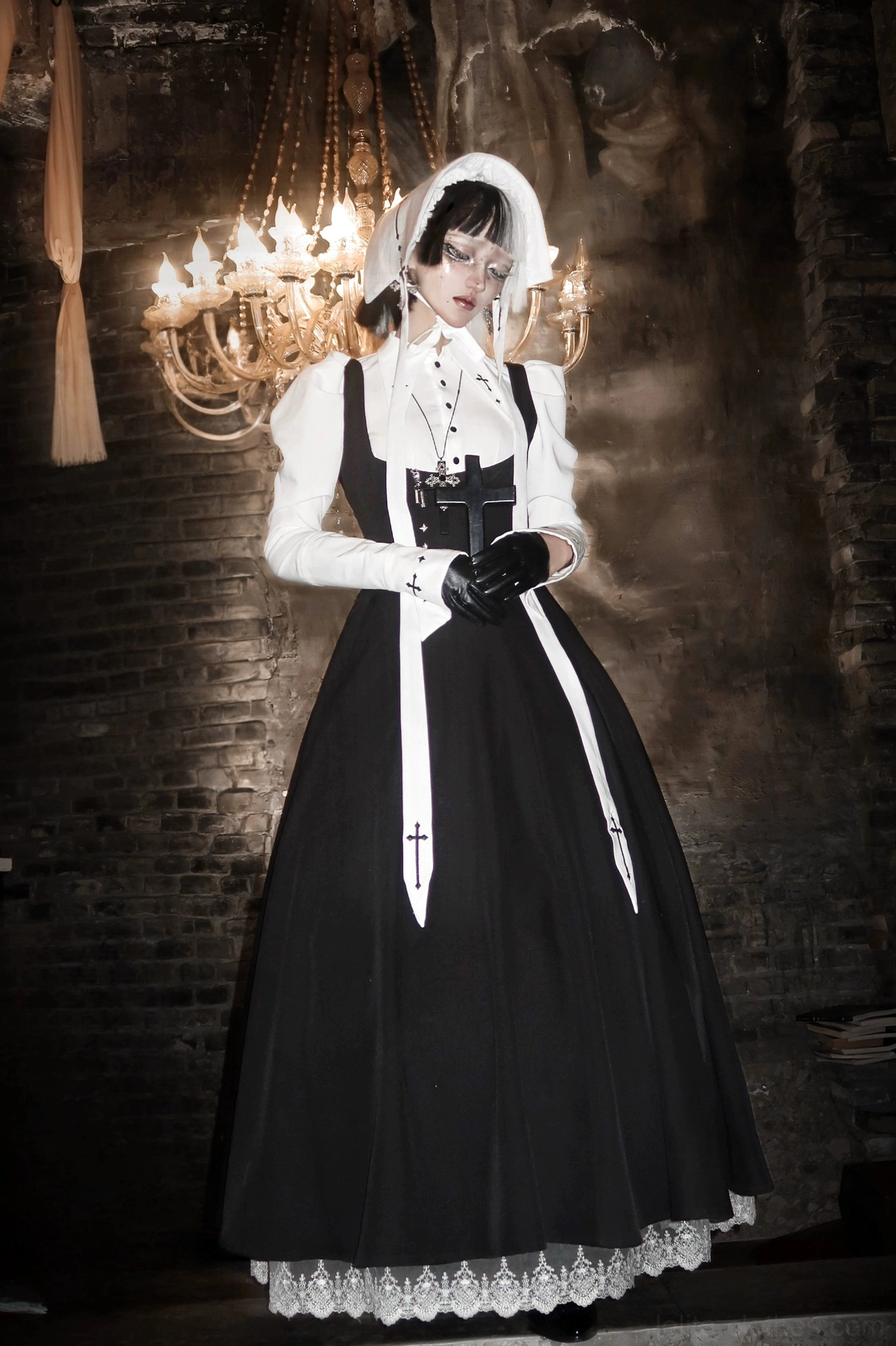 Gothic nun-style lolita set in vintage ballroom with ornate chandelier, black flared JSK with lace hem, white puff-sleeve blouse and formal gloves