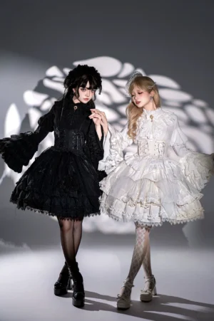 Black and white gothic lolita dress set shown on two models side by side demonstrating contrasting dark and light interpretations with full princess sleeves and tiered ruffles