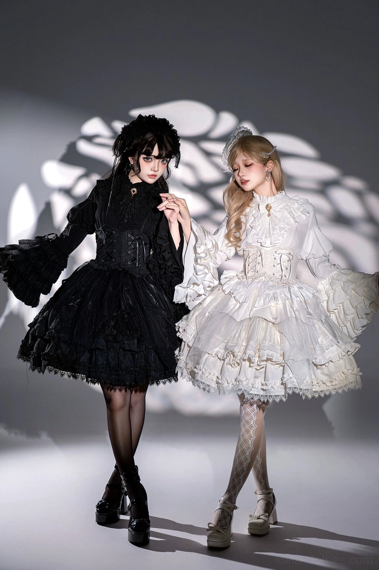 Black and white gothic lolita dress set shown on two models side by side demonstrating contrasting dark and light interpretations with full princess sleeves and tiered ruffles