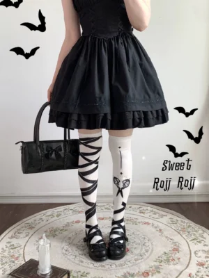 Black and white asymmetric gothic lolita over-knee socks with scissors print worn by model in complete Gothic lolita coordinate with black ruffled dress platform shoes and accessories
