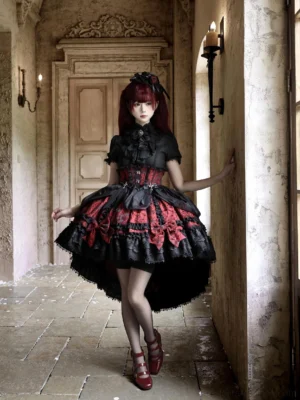Black and red gothic lolita high-low skirt set with detachable cross bows worn outdoors on vintage stone paved corridor showing corset waist and ruffled hem