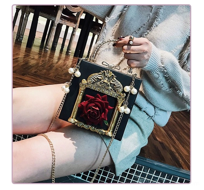 Model wearing black gothic lolita square crossbody bag with red rose and gold baroque frame paired with light blue frayed knit sweater