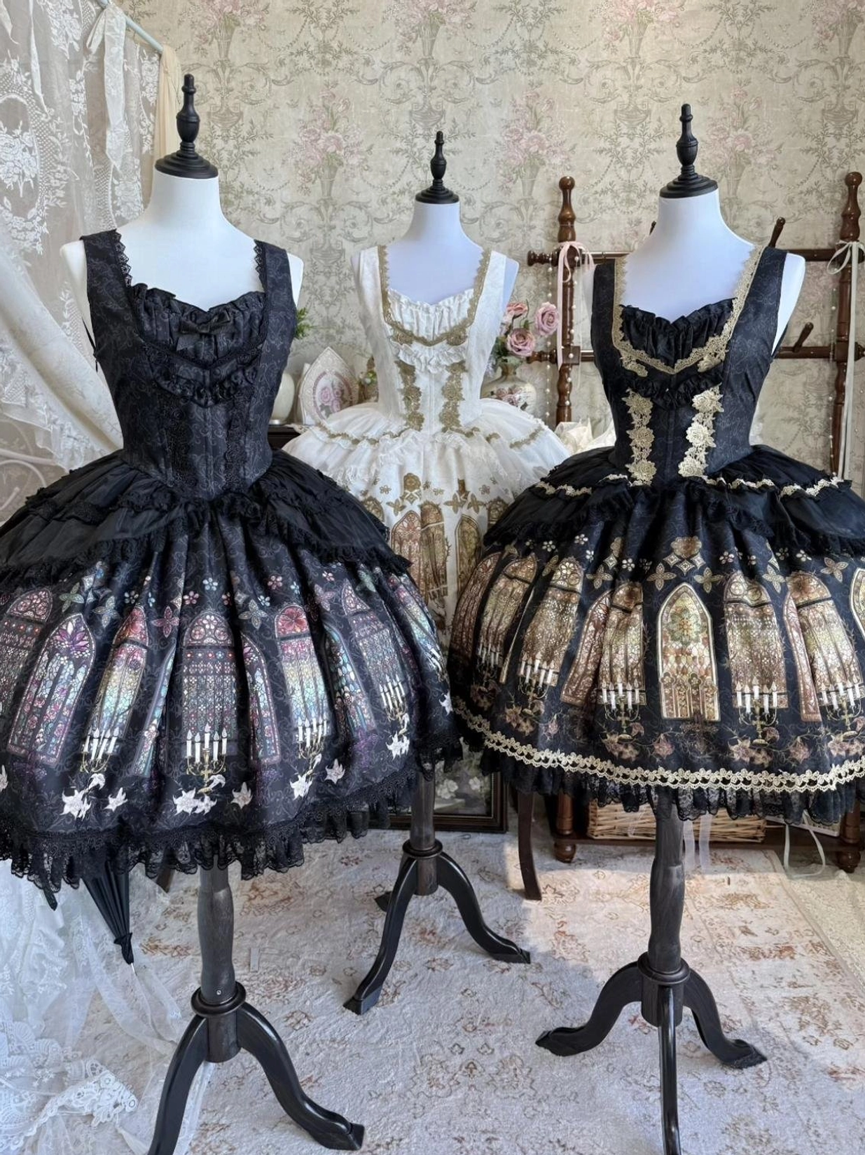 Matching black and white gothic lolita stained glass print JSK dresses with gold embroidery displayed in vintage boutique setting