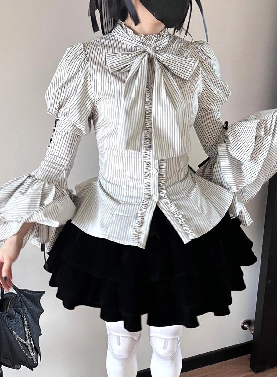 White and black striped Gothic Lolita blouse worn by model showing large bow jabot, front button closure and puffed sleeves paired with black velvet tiered skirt and white thigh-high stockings