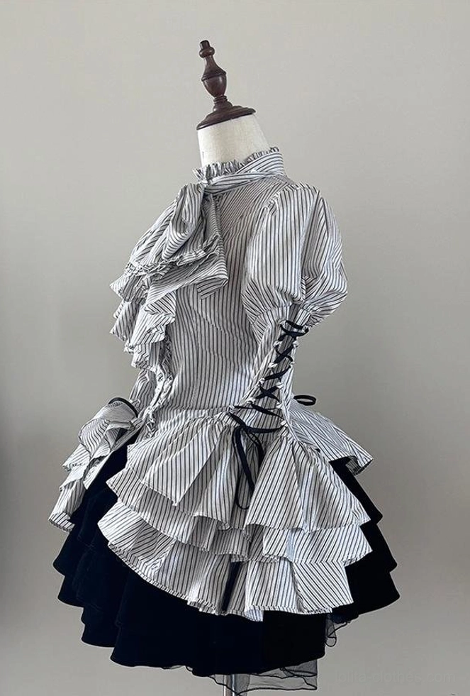 Styled flat-lay composition of Gothic Lolita striped blouse with matching necktie and jabot accessories arranged with complementary styling elements and props