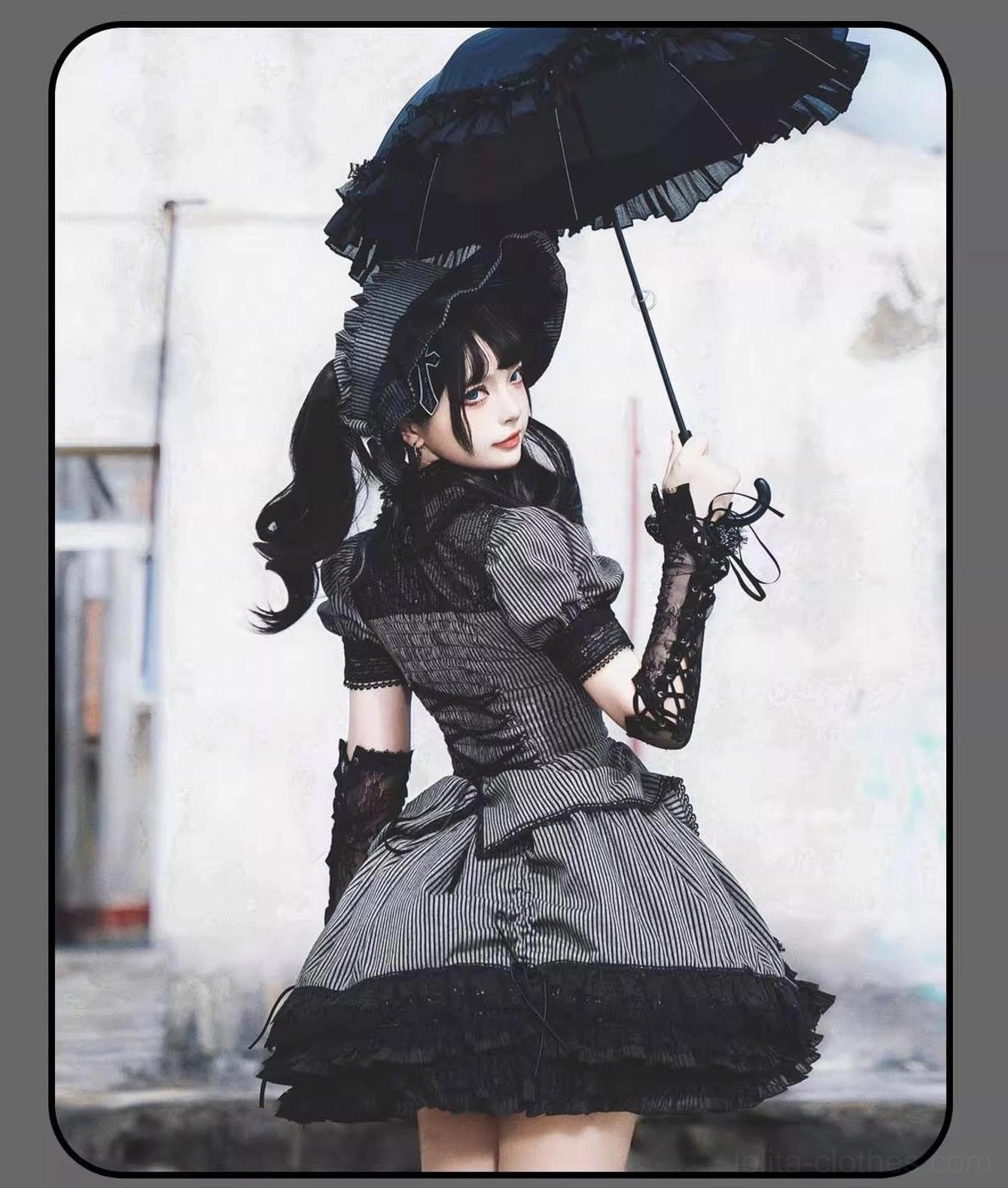 Striped Gothic Lolita back view showing vertical stripe pattern and tiered ruffled skirt hem with lace elbow gloves and frilled hair accessory