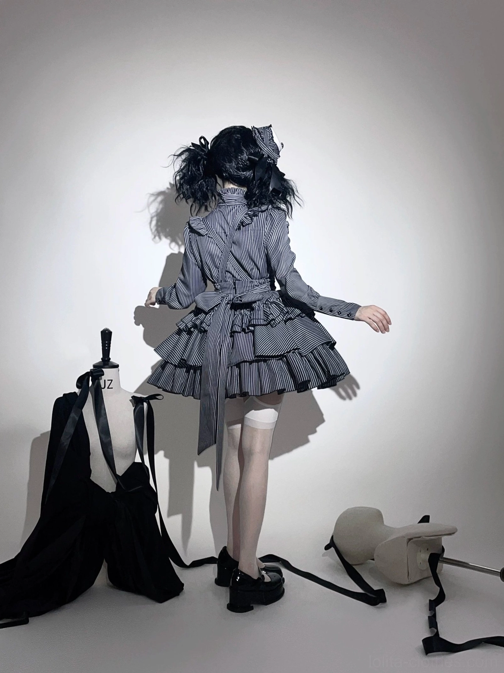 Back view of grey gothic lolita outfit showing back zipper closure and tiered ruffled skirt design with waist sash detail