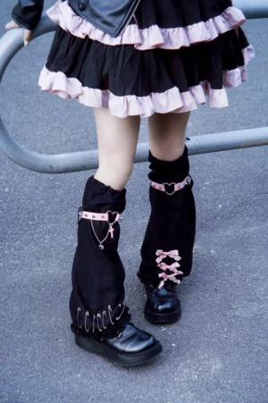Full front view of pair of gothic suede leg warmers featuring studded cuffs pink decorative straps metal charms heart buckles worn with ruffle lolita skirt