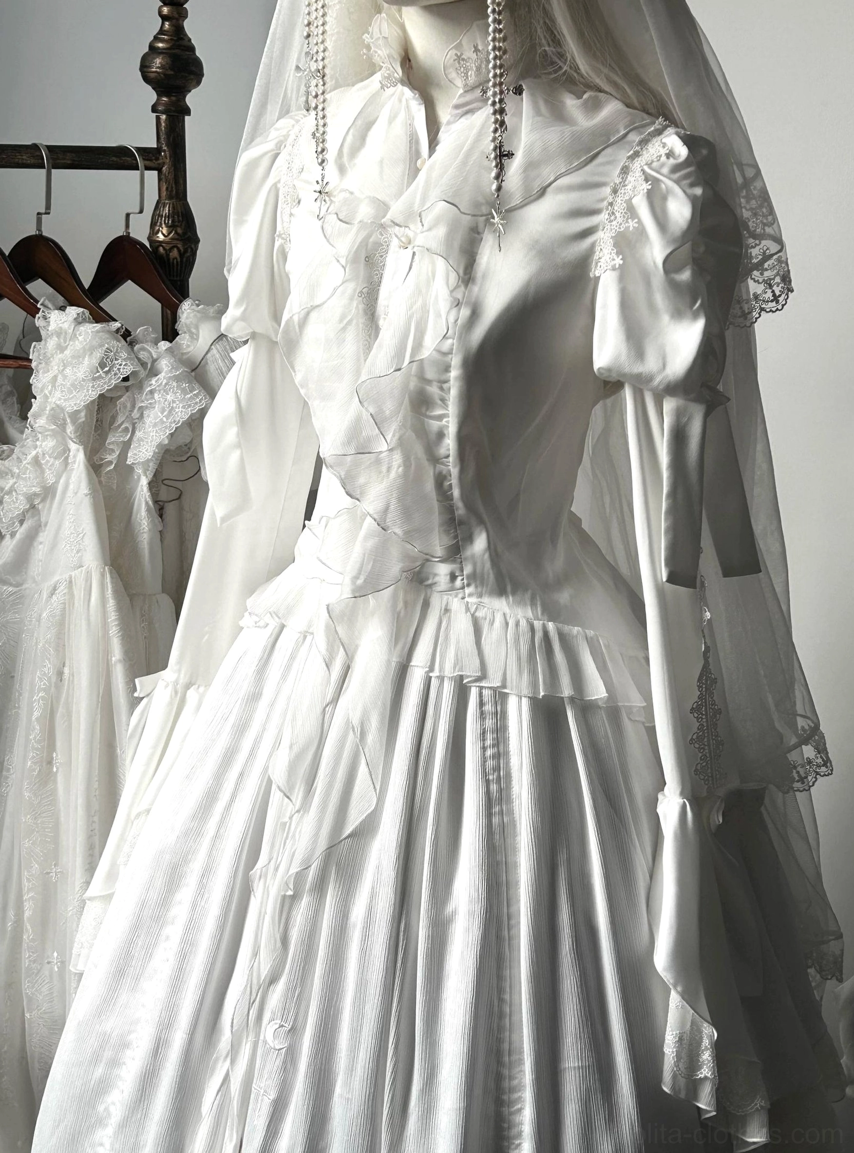 Gothic lolita blouse three-quarter angle detail showing irregular swallowtail hem construction, lace paneling, and puffed sleeve silhouette on mannequin