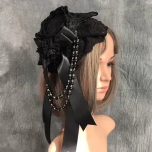 Gothic Lolita mini top hat with detachable beaded chain displayed on mannequin head - right three-quarter angle showing black lace ruffles, satin bow with fabric rose, and dual-layer beaded tassel chains